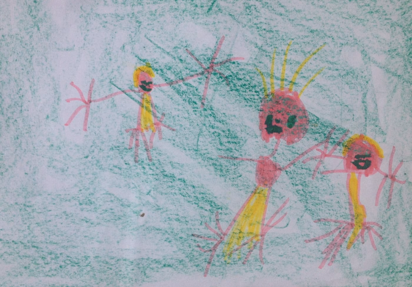 Dessin d'enfant aux feutres : trois personnages roses et jaunes aux bras et jambes en bâtons, sur un fond colorié en vert.